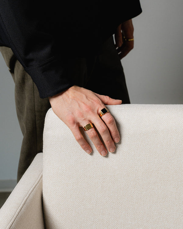 Ein Mann traegt zwei goldene Ringe den Siegelring mit schwarzem Onyx und den Edgy Ring beide gefertigt aus 925 Silber mit 18k Vergoldung fuer edlen Stil Sprezzi Fashion