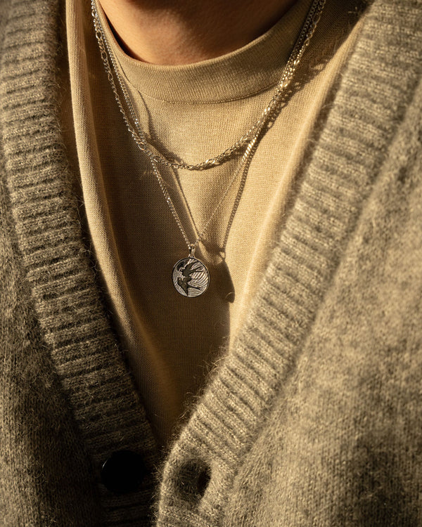 Model traegt Figaro und Peace Dove Halsketten aus 925 Silber der glaenzende Gliederschliff und der feine Taubenanhaenger zeigen maskuline Eleganz Sprezzi Fashion