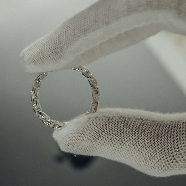 Detailaufnahme eines Silberrings im Seil Design zeigt fein gedrehte Struktur und präzise Verarbeitung gehalten zwischen Fingern mit elegantem Erscheinungsbild Sprezzi Fashion