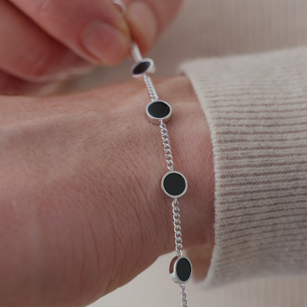 Das Onyx Armband aus 925 Sterling Silber liegt am Handgelenk, während die runden schwarzen Steine gleichmäßig entlang der Kette verteilt sind und eine klare, moderne Anordnung zeigen Sprezzi Fashion