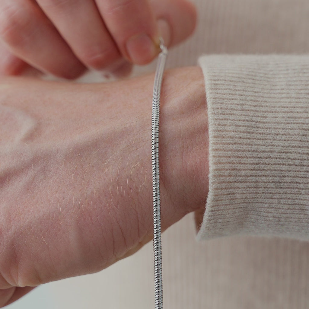 Detailansicht eines 925 Silber Snake Armbands, dessen glatte Struktur eine durchgehende Lichtreflexion erzeugt und die hochwertige, fließende Oberfläche betont Sprezzi Fashion