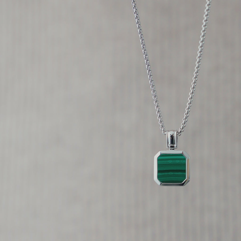Nahaufnahme einer Herren Halskette aus 925 Sterling Silber mit eckigem grünem Malachit Stein Anhänger, die polierte Oberfläche reflektiert das Licht und hebt die natürliche Maserung des Steins klar hervor Sprezzi Fashion
