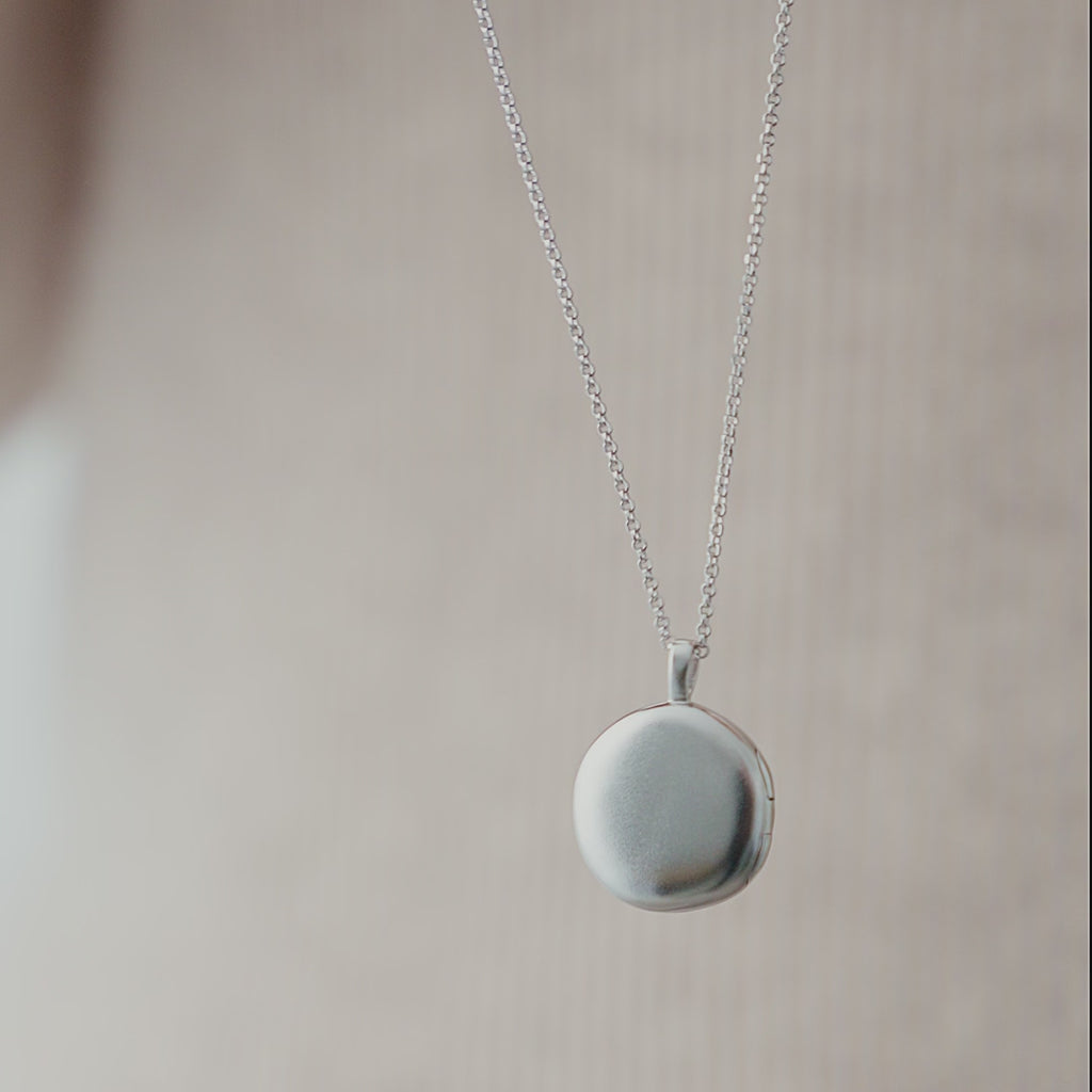 Detailansicht eines runden Medaillon Anhängers aus 925 Silber mit gebürsteter Oberfläche, die einen sanften Verlauf im Licht erzeugt und die klare, minimalistische Gestaltung unterstreicht Sprezzi Fashion